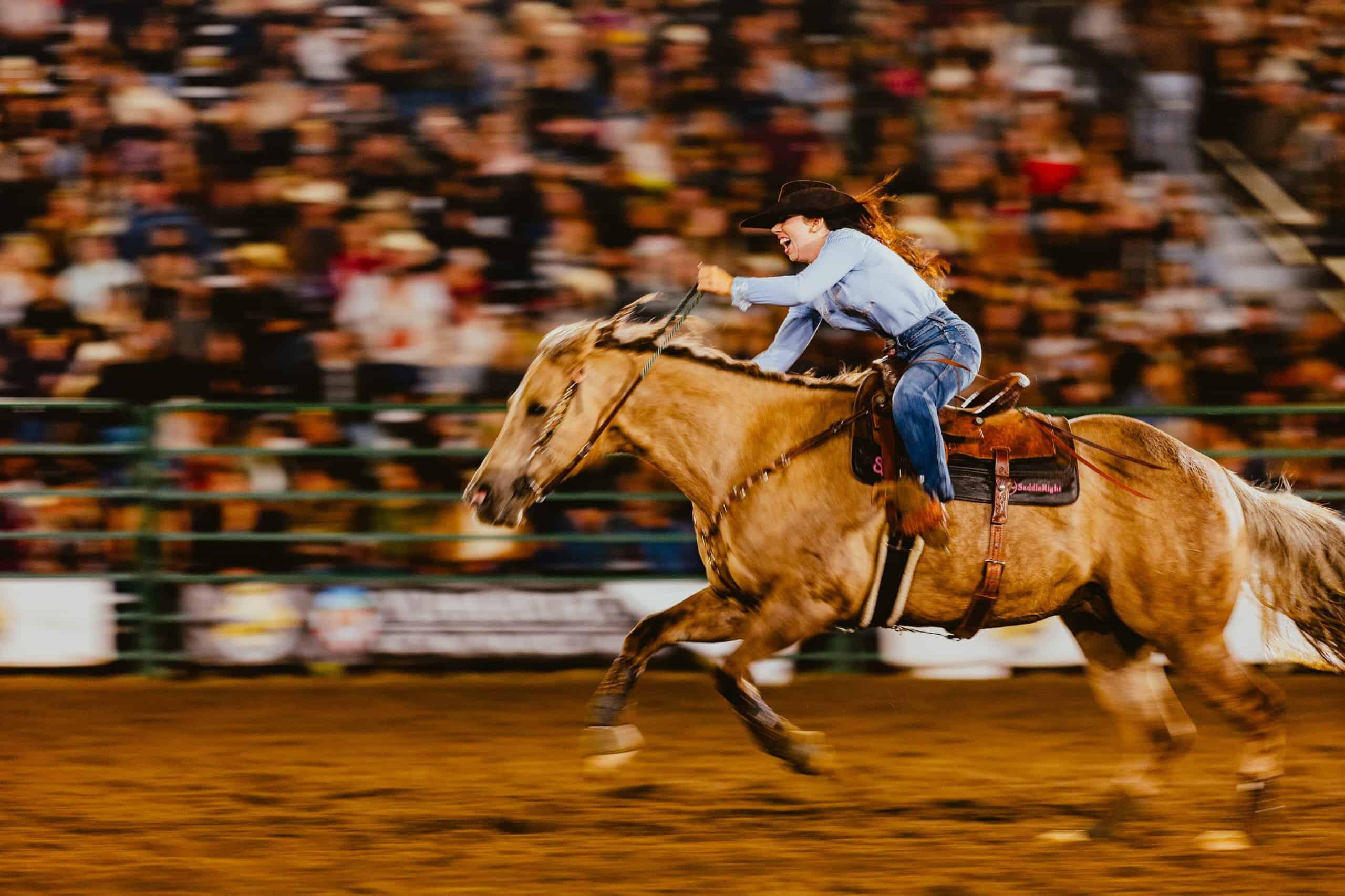 A woman riding a horse at full gallop, using PopUp WiFi event internet for live streaming the show live to the Cowboy Channel.