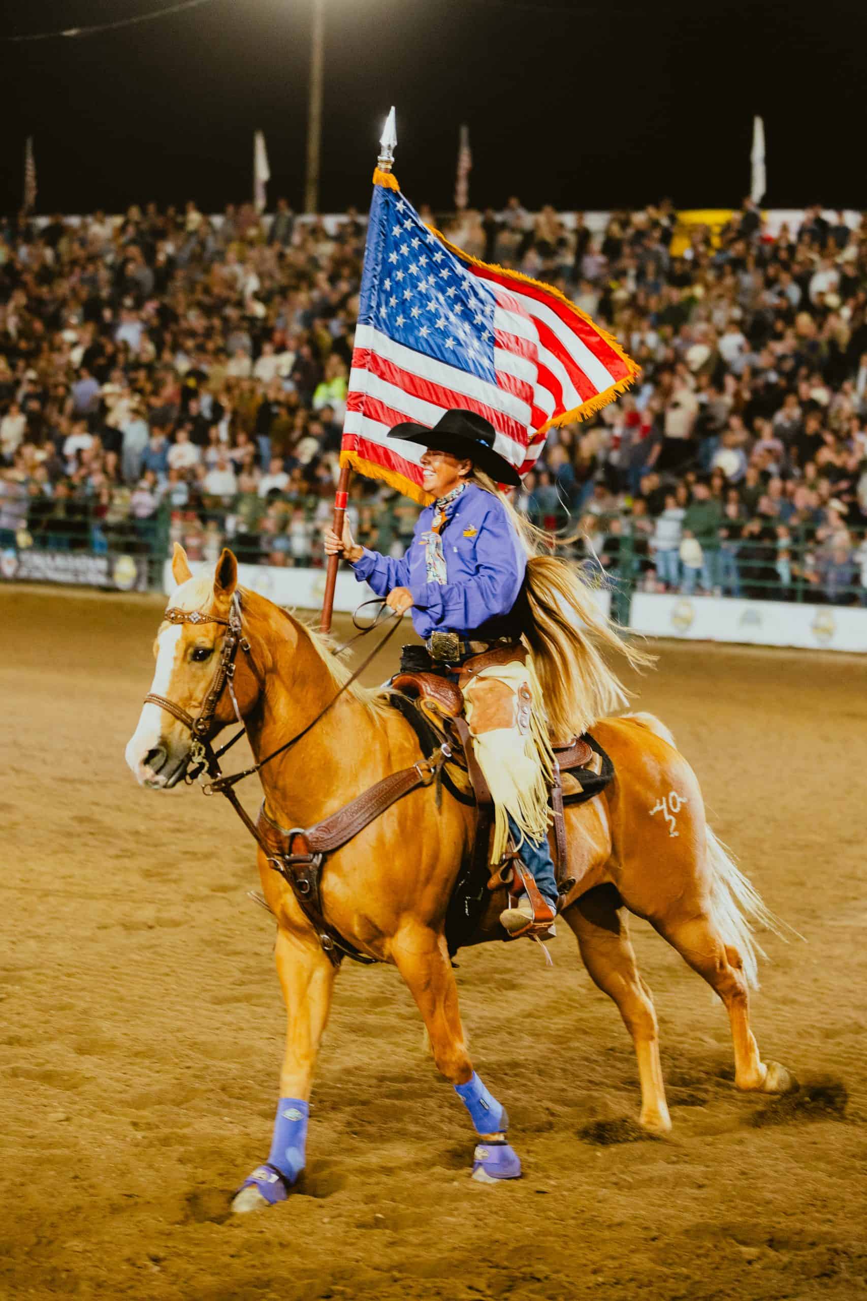 A woman galloping a horse and holding US flags with a crowd while PopUp WiFi event internet is used to broadcast the event live.