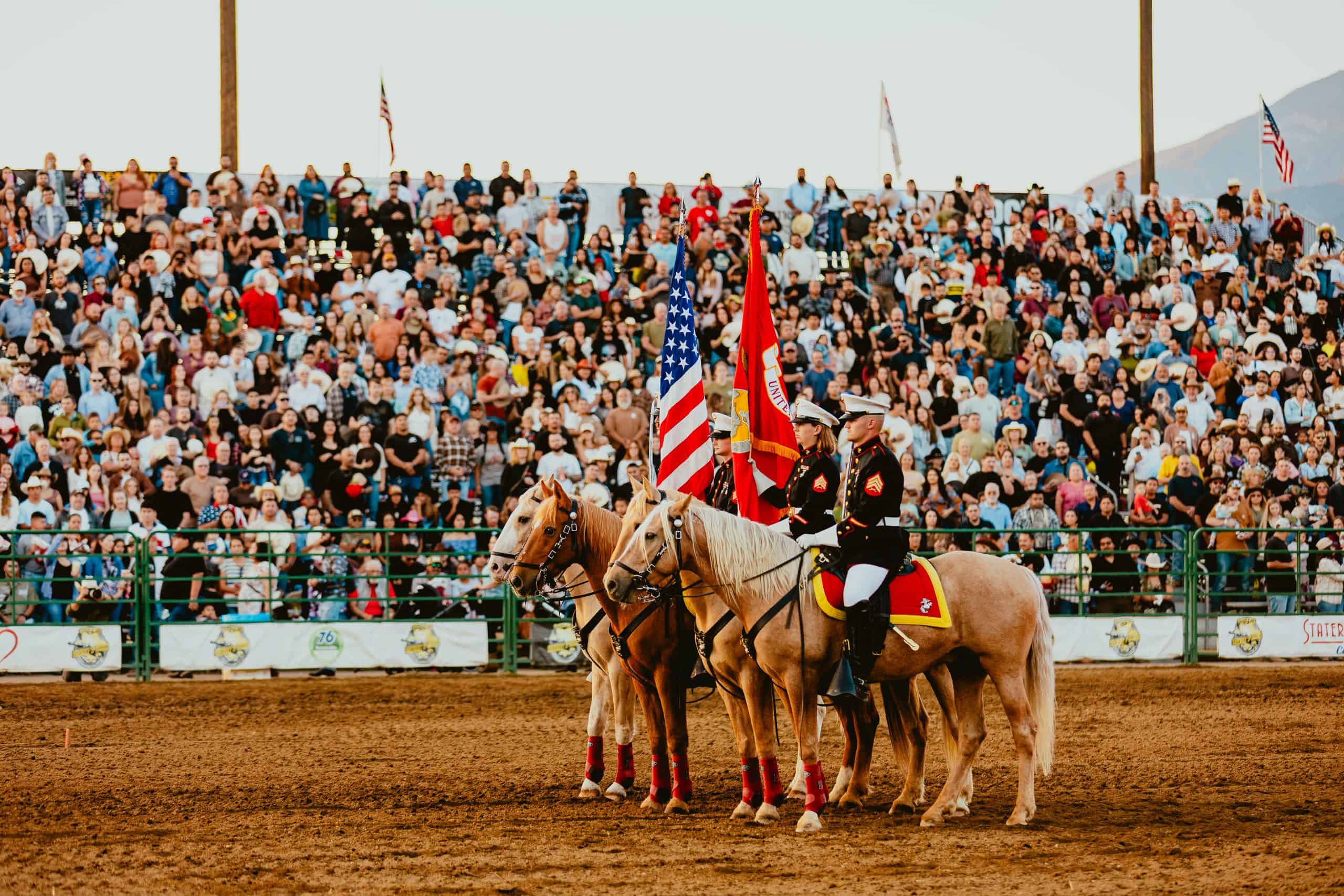 Two people on horses holding US flags with a crowd while PopUp WiFi event internet is used to broadcast the event live.