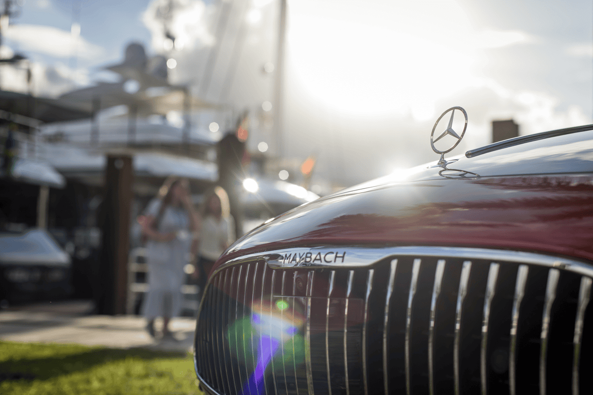 A Mercedes Benz in the foreground and a super yacht in the background.