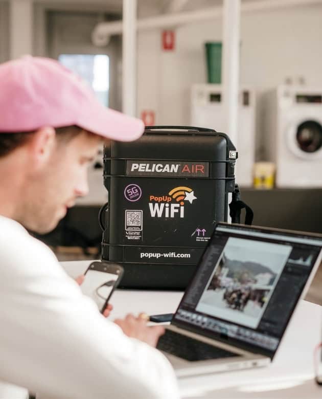 Man using PopUp WiFi internet rental unit to upload and edit media from an event.