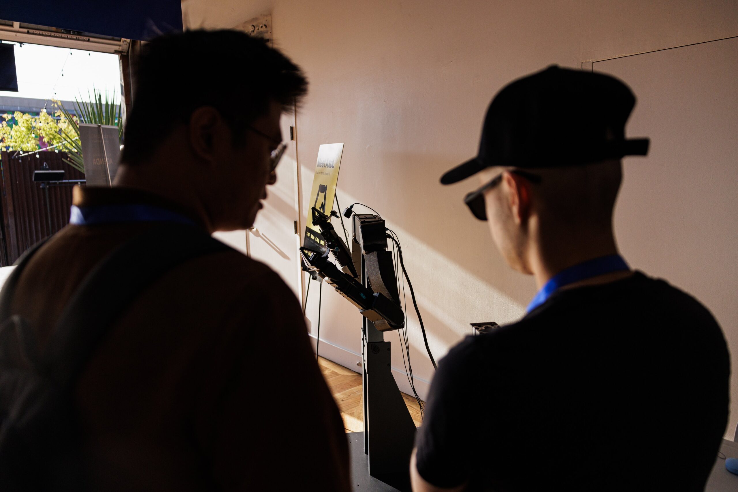 Two attendees viewing a "Meet Axel" robotics demo unit near an open patio doorway during AUTONOMOUS 2026 networking hours with connectivity provided by PopUp WiFi
