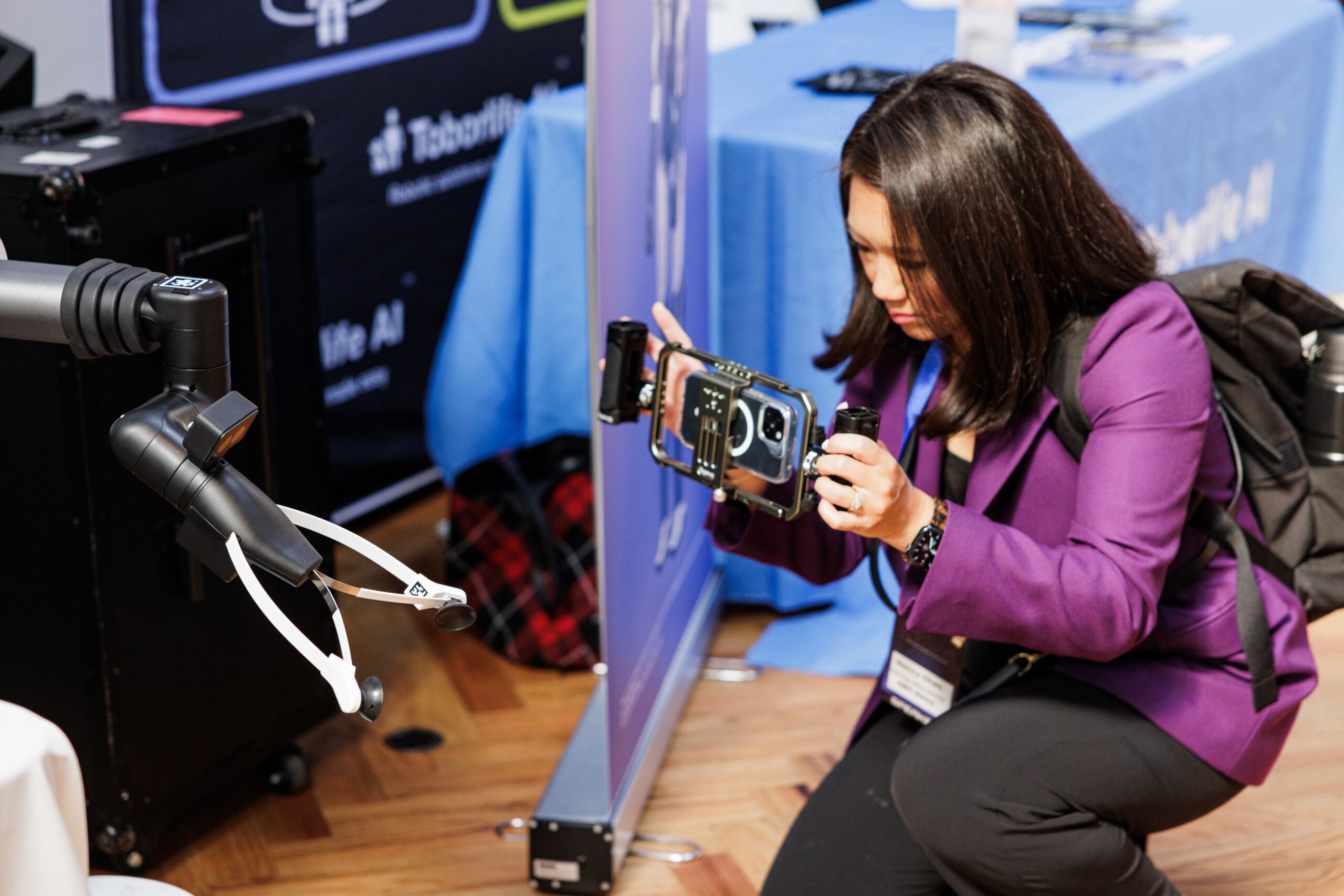Attendee filming a robotic arm holding a smartphone camera rig at the Toborlife AI booth during AUTONOMOUS 2026 powered by PopUp WiFi