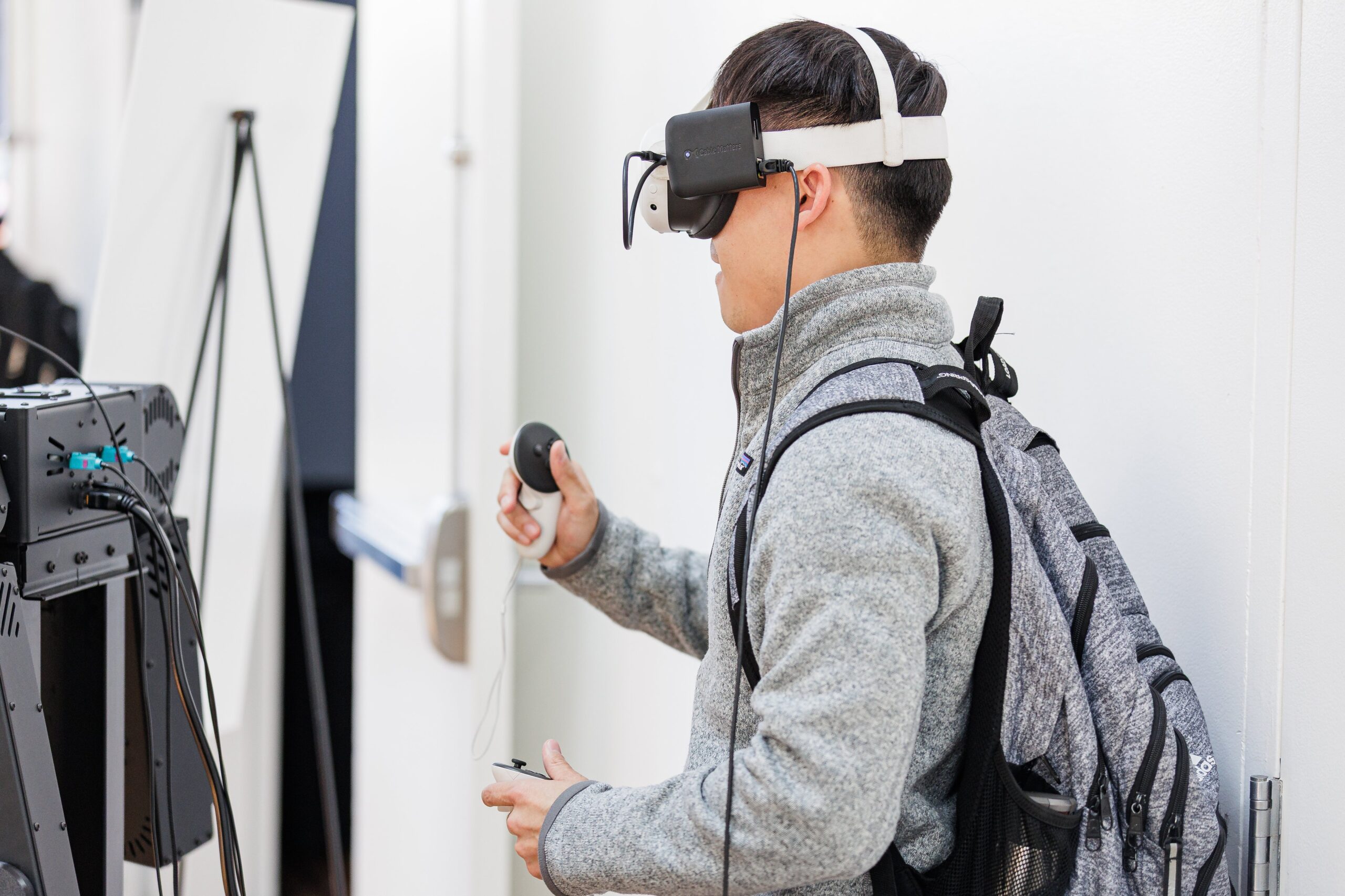 Conference attendee wearing a VR headset and holding motion controllers at a robotics demo station during AUTONOMOUS 2026 in San Francisco