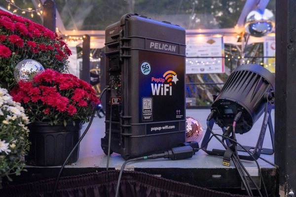 A PopUp WiFi 5G unit on the edge of a tented stage among red mums, disco balls and stage lights at Sweat For Good Games, New Hampshire